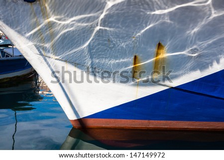 Reflections of the water on the hull of boat anchored at a marina