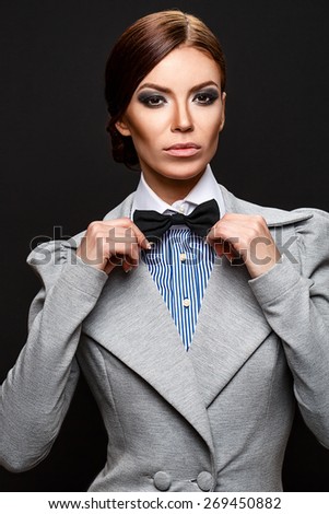 Beautiful business woman in suit fixing her bow tie