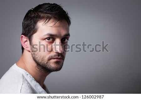 Young handsome man with serious expression on dark background