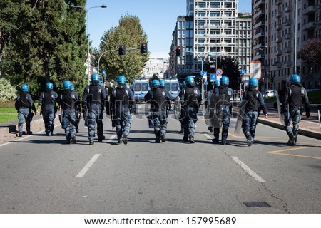 MILAN, ITALY - OCTOBER 11: Riot police follows secondary school students marching in the city streets to protest against money cuts in the public school on OCTOBER 11, 2013 in Milan.