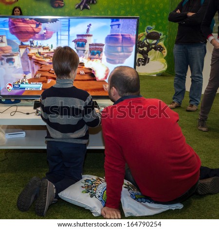 MILAN, ITALY - NOVEMBER 22: Father and son play video games at G! come giocare, trade fair dedicated to games, toys and children on NOVEMBER 22, 2013 in Milan.