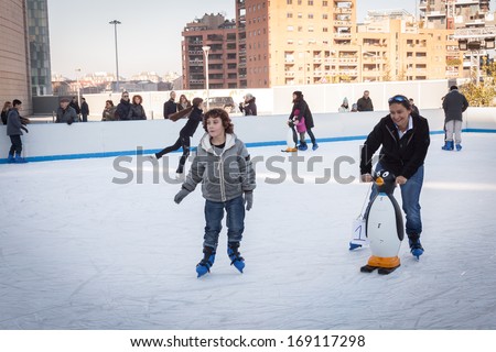 MILAN, ITALY - DECEMBER 27: People have fun skating on a public ice rink built up in the city streets by Municipality during the Christmas period on DECEMBER 27, 2013 in Milan.