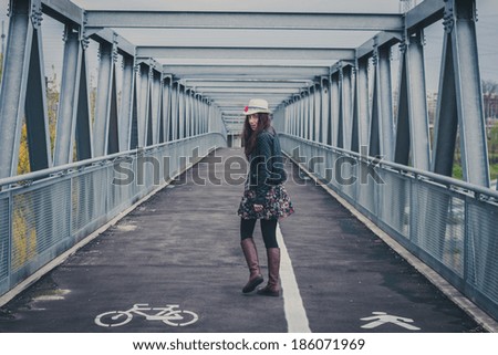 Pretty girl with long hair walking away on a bridge