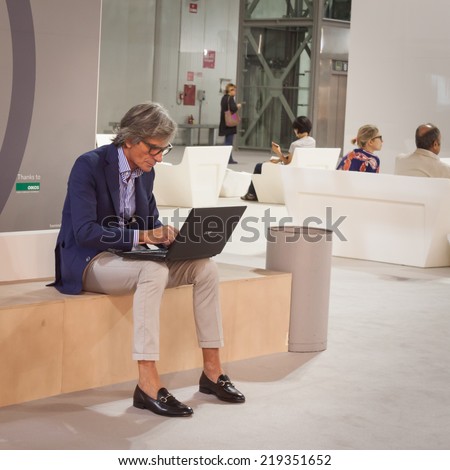 MILAN, ITALY - SEPTEMBER 13: Stylish man working at computer at HOMI, home international show and point of reference for all those in the sector of interior design on SEPTEMBER 13, 2014 in Milan.