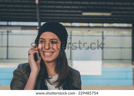 Pretty girl with beanie talking on phone in a metro station