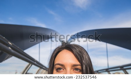 Detail of a beautiful young brunette with long hair posing on a bridge