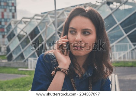 Pretty girl with long hair talks on phone in the street