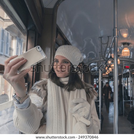 Beautiful young woman wearing ecological fur takes a selfie on a tram - Concept of sustainable mobility