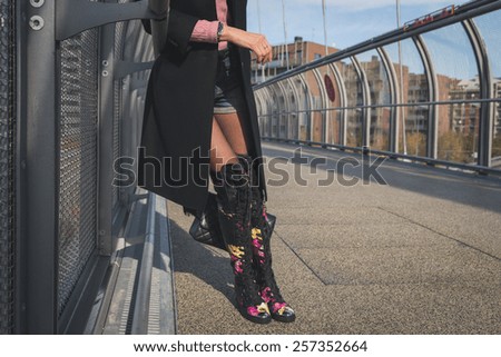 Detail of a beautiful young brunette with over the knee boots posing on a bridge