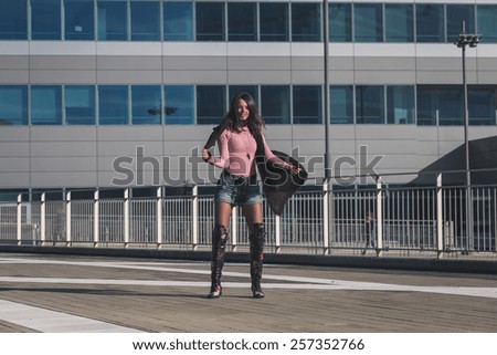 Beautiful young brunette with over the knee boots posing in the city streets