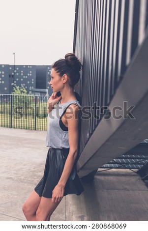 Gorgeous young brunette in black skirt posing in an urban context