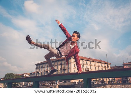 Young handsome Asian model dressed in red blazer jumping a balustrade