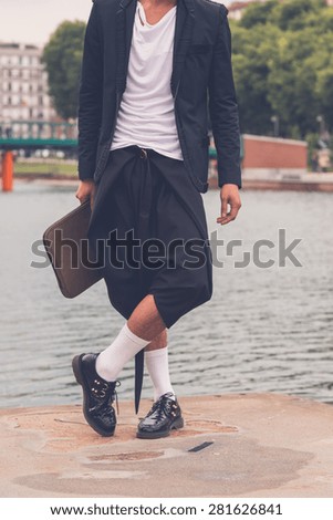 Young handsome Asian model dressed in black posing by an urban artificial basin