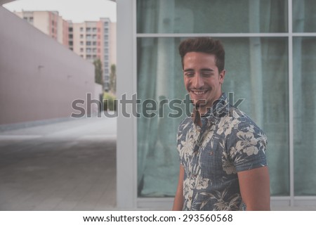Young handsome man with short hair wearing a short sleeve shirt and posing in an urban context