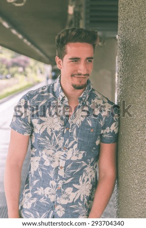 Young handsome man with short hair wearing a short sleeve shirt and posing in a metro station