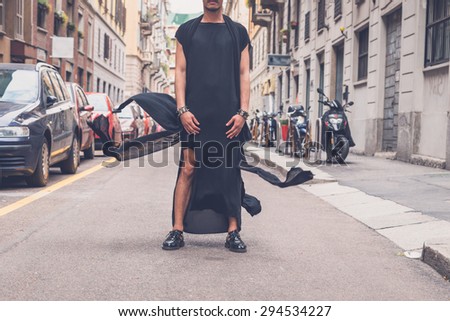 Young handsome Asian model dressed in black tunic posing in the city streets