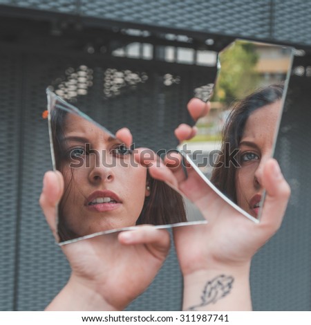 Beautiful young girl with blue eyes looking at herself in a broken mirror