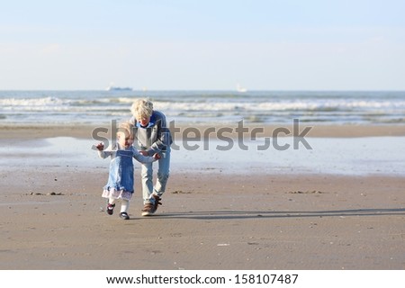Happy kids, brother and sister, playing and running on the beach on a warm sunny day