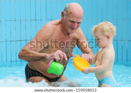 Sportive grandfather with grandchild having fun together playing in swimming pool