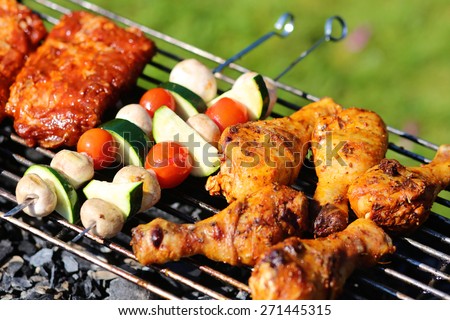 Assorted meat from chicken and pork and various vegetables on barbecue grill cooked for summer family dinner