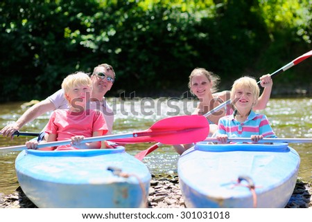 Parents and kids kayaking on the river. Active happy family, father, mother and two teenage school boys, having fun together enjoying adventurous experience on a sunny day during summer vacation.