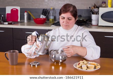 Middle-aged housewife pouring boiling water on tea-bag to make tea