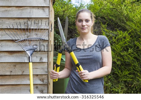 Portrait of pretty girl with horticultural sundry near backyard shed