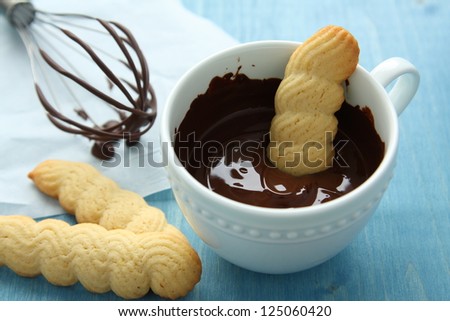 Cup of chocolate with shotrbread cookies and whisk on blue wooden background