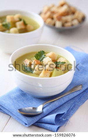 Creamy sweet potato soup with croutons and parsley in white bowl