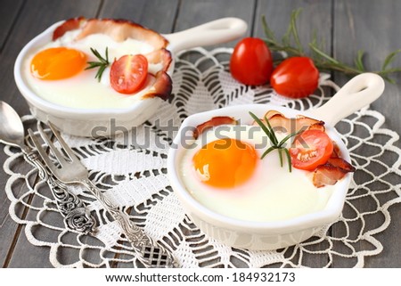 Fried egg with bacon and tomato in ceramic pan