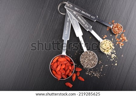 Superfoods. Goji berries, chia seeds, hemp seeds and broken flax seeds in metal measuring spoons