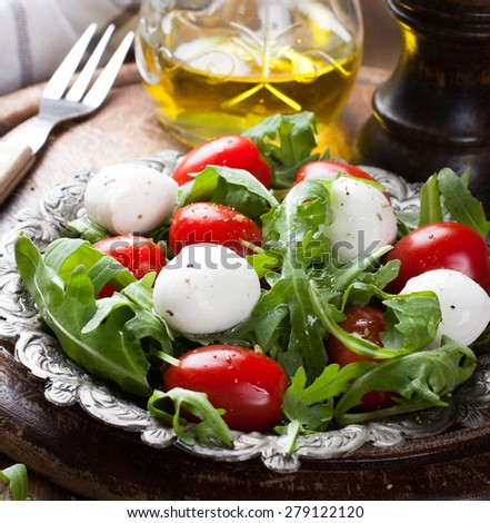 Fresh italian salad with mozzarella cheese, tomato and rucola on vintage old metal plate. Healthy food. Selective focus.