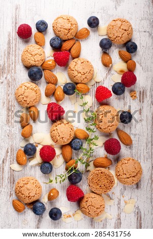 Italian almond cookie amaretti, blueberries, raspberry, thyme sprigs and almonds on white vintage table, food concept, top view.