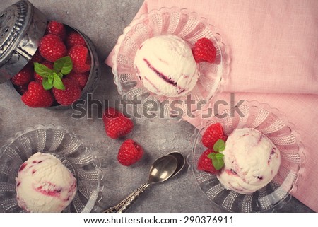 Delicious berry ice cream on glass plate decorated with fresh raspberries on vintage gray background. Top view. Selective focus. Retro style toned. Party concept.