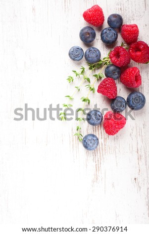 Berries on White Wooden Background. Summer or Spring Organic Berry over Wood. Raspberries, Blueberry and thyme. Haelthy food, Gardening, Harvest Concept. Copy space.