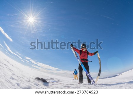 woman taking the skins off of her touring skis on a plateau in the wind