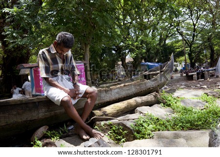 COCHIN-SEPTEMBER 2012: An old fisherman falls asleep sitting atop his canoe on september 5, 2012 in Cochin, India.