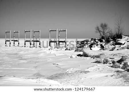 Pilings for a pier have been frozen during a harsh winter. Photo is black and white.