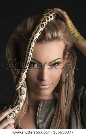 Portrait of beautiful woman in studio with dangerous snake