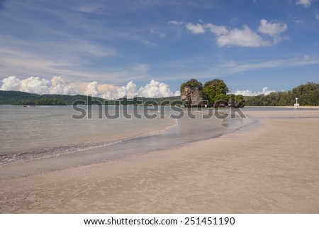 Sandy beach, rocky island, boat and lighthouse