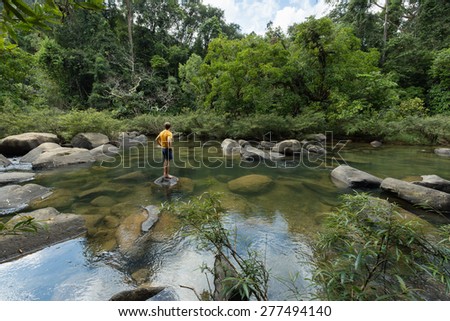 Man standing in idyllic Jungle pool surrounded by lush green rain forest in Khao Sok National Park, Thailand