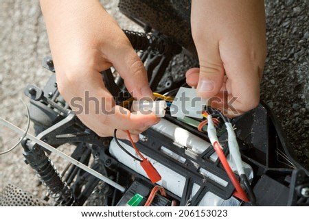 Little boy repaire the radio control car outdoor near field