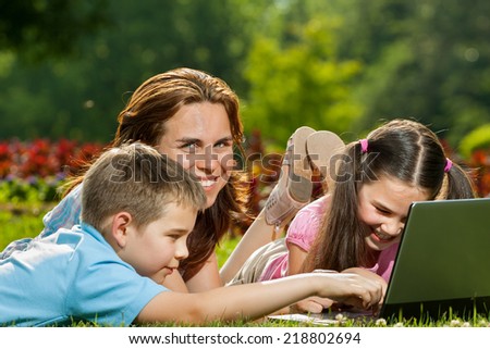 Happy family having fun outdoors with a laptop computer