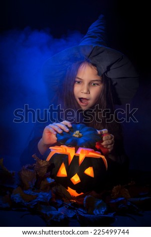 Little witch conjures up a halloween pumpkin in smoke