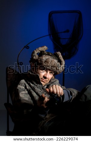 The fishing man in photo studio in old fishing clothes with fishing rod