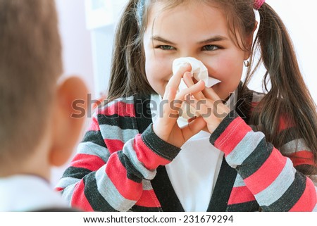 A sweet little girl sneezing into a tissue while her pediatrician sits and looks on worriedly