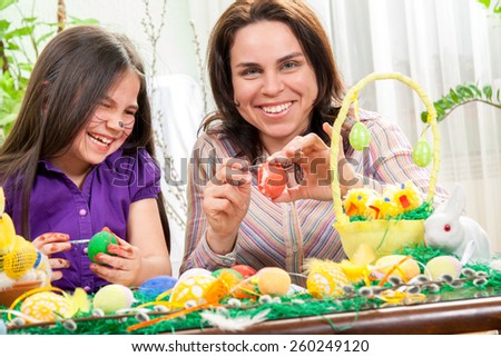 Mother showing to her children how to paint  Easter eggs