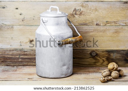 Walnuts and an aluminum old milk can on a wooden background