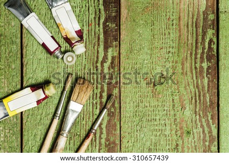 Paint brushes set and oil paint tubes on a green wooden background