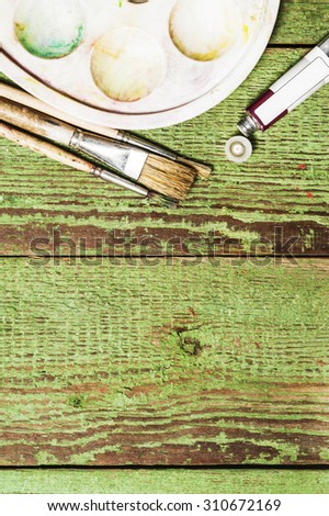 Paint brushes set and a palette with an oil paint tube on a green wooden background